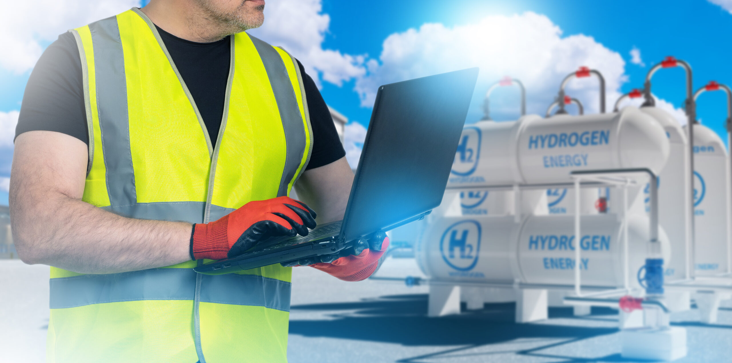 Hydrogen power plant technologist. man with laptop near h2 gas tanks. Sweco Fab offers custom fabricated pressure vessels to help with sustainable energy.