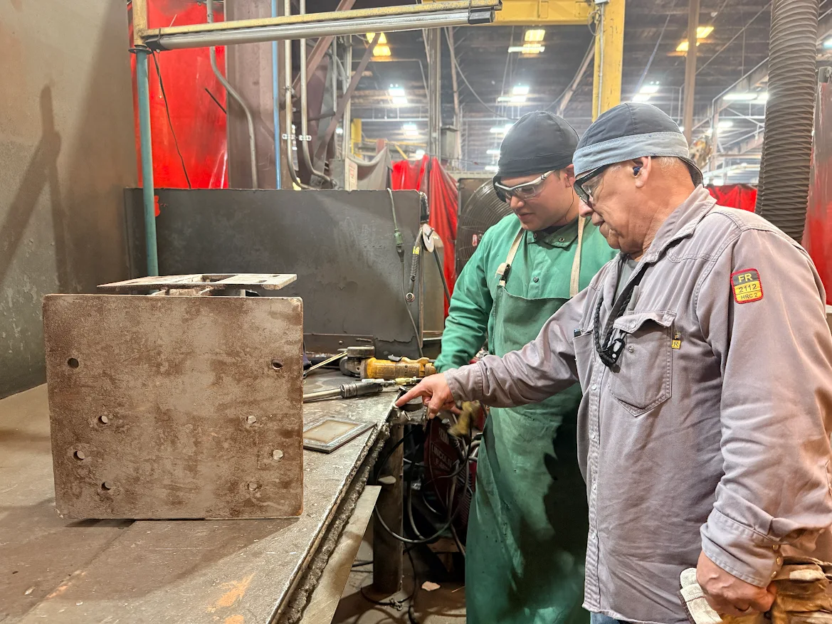 Pete hidalgo works with a welding school student.
